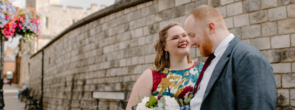 Our Wedding Day A photo from our wedding day. My wife and I are standing in front of a castle I am smiling to myself, and she is smiling at me. We are both dressed up ready to get married.
